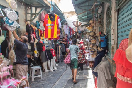 Téléchargez les photos : Commerce dans l'ancienne Médina de Tunis en Tunisie. Des vêtements vendus pour les touristes. Vêtements traditionnels. - en image libre de droit