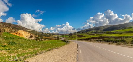 Photo for A Scenic Drive Through Mountains and Green Fields Under a Blue Sky with Clouds in Tunisia - Royalty Free Image