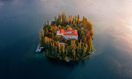 Photo for Visovac, Croatia - Aerial view of the amazing Visovac Christian monastery in Krka National Park on a bright autumn morning with warm golden lights at sunrise and blue water - Royalty Free Image