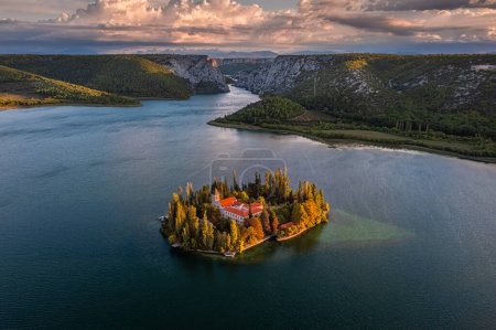 Photo for Visovac, Croatia - Aerial view of Visovac Christian monastery in Krka National Park on a bright autumn morning with dramatic golden sunrise and clear turquoise blue water - Royalty Free Image