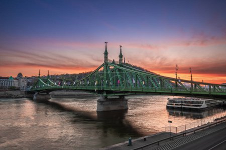 Foto de Budapest, Hungría - Vista panorámica del Puente de la Libertad al atardecer con la Colina Gellert y la Estatua de la Libertad y el cielo dorado al atardecer al fondo - Imagen libre de derechos