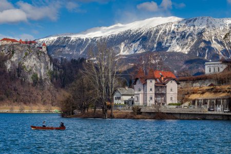 Foto de Bled, Eslovenia - Lago Bled con barco pequeño y el castillo de Bled y los Alpes Julianos en el fondo en un día soleado de invierno - Imagen libre de derechos