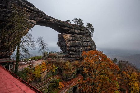 Téléchargez les photos : Hrensko, République tchèque - Le célèbre Pravcice Brana (Pravcicka Gate) dans le parc national de la Suisse bohème, le plus grand arc naturel d'Europe par une journée brumeuse avec un feuillage d'automne coloré - en image libre de droit