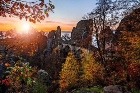 Photo for Saxon, Germany - Beautiful view of the Bastei bridge on a sunny autumn sunrise with colorful foliage. Bastei is famous for the beautiful rock formation in Saxon Switzerland National Park near Dresden - Royalty Free Image