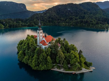 Foto de Lake Bled, Slovenia - Aerial view of Pilgrimage Church of the Assumption of Maria at Lake Bled (Blejsko Jezero) with Julian Alps at backgroud on a summer afternoon with golden sunset sky - Imagen libre de derechos