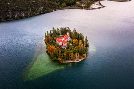 Téléchargez les photos : Visovac, Croatia - Aerial view of the beautiful island Visovac Christian monastery in Krka National Park on a bright autumn morning with autumn foliage and blue water - en image libre de droit