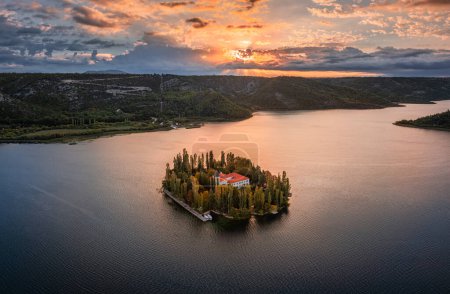 Foto de Visovac, Croatia - Aerial panoramic view of Visovac Christian monastery in Krka National Park on a bright autumn morning with dramatic golden sunrise and clouds and clear turquoise blue water - Imagen libre de derechos