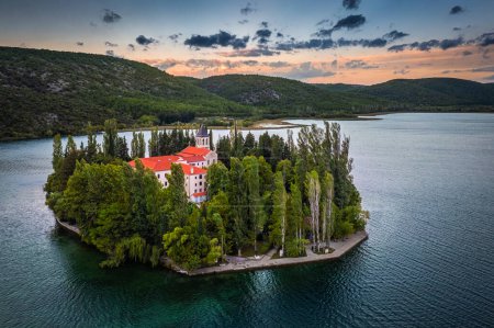 Téléchargez les photos : Visovac, Croatia - Aerial view of Visovac Christian monastery island in Krka National Park on a summer morning with green foliage, golden and blue sky at background at sunrise - en image libre de droit