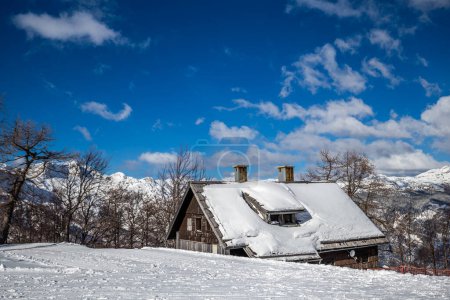 Photo for Bohinj, Slovenia - Winter view of the snowy ski hut at the top of Vogel mountain in the Alps at Triglav National Park on a sunny winter day with blue sky and clouds - Royalty Free Image