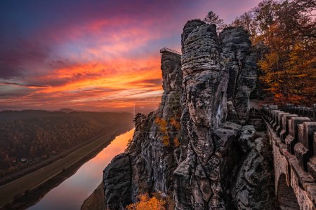 Foto de Sajón, Alemania - Hermosa formación rocosa del puente Bastei con espectacular puesta de sol colorida de otoño sobre el río Elba en una tarde de noviembre en el Parque Nacional Sajón Suiza - Imagen libre de derechos
