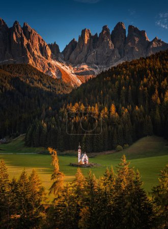 Téléchargez les photos : Val Di Funes, Dolomites, Italie - La belle église St. Johann in Ranui au Tyrol du Sud avec les Dolomites italiennes et le ciel bleu en arrière-plan avec des lumières chaudes de coucher de soleil d'automne - en image libre de droit