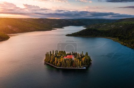 Téléchargez les photos : Visovac, Croatia - Aerial panoramic view of Visovac Christian monastery in Krka National Park on a bright autumn morning with dramatic golden sunrise and clouds and clear turquoise blue water - en image libre de droit