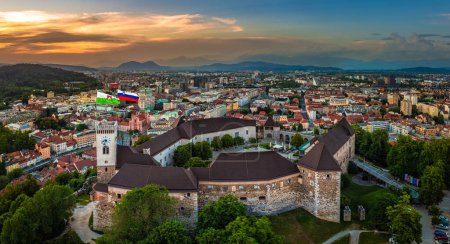 Téléchargez les photos : Ljubljana, Slovénie - Vue panoramique aérienne du château de Ljubljana par un après-midi d "été avec l" église franciscaine de l'Annonciation, la cathédrale de Ljubljana et l'horizon de la capitale slovène avec un coucher de soleil d "été doré - en image libre de droit