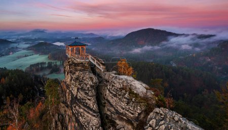 Jetrichovice, Czech Republic - Aerial panoramic view of Mariina Vyhlidka (Mary's view) lookout with foggy Czech autumn landscape and colorful pink sunrise sky in Bohemian Switzerland region