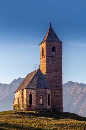 Téléchargez les photos : Hafling, Italie - L "église de montagne Sainte-Catherine (Chiesa di Santa Caterina) près de Hafling - Avelengo sur un coucher de soleil d'automne chaud avec les Dolomites italiennes dans le Tyrol du Sud en arrière-plan - en image libre de droit