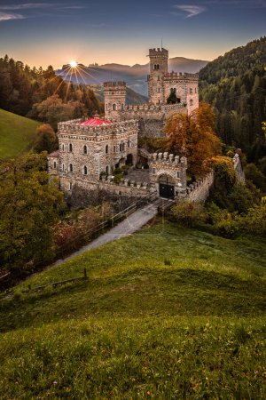 Latzfons, Italie - Beau paysage d'automne au château de Gernstein (Castello di Gernstein, Schloss Gernstein) au lever du soleil dans le Tyrol du Sud avec ciel bleu et feuillage doré et fleurs au premier plan