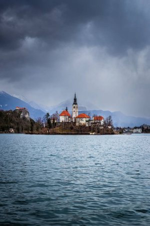 Téléchargez les photos : Lac de Bled, Slovénie - Belle vue sur le lac de Bled (Blejsko Jezero) avec l "église de pèlerinage de l'Assomption de Marie sur l" île de Bled, le château de Bled et les Alpes juliennes en arrière-plan en hiver - en image libre de droit