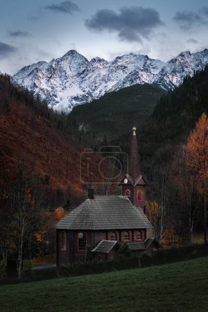Tatranska Javorina, Slowakei - Schöne römisch-katholische Holzkirche St. Anna bei dem Dorf Tatranska Javorina an einem bewölkten Herbsttag mit den schneebedeckten Gipfeln der Hohen Tatra im Hintergrund