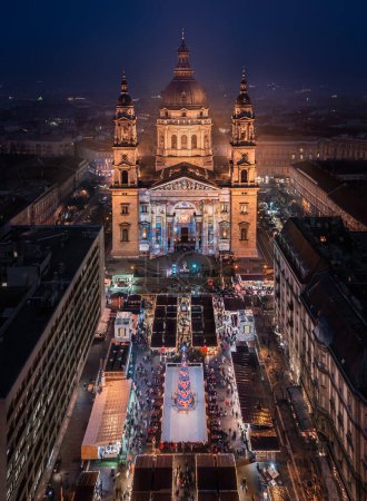Photo for Budapest, Hungary - Aerial view of Europe's most beautiful Christmas market at the illuminated St.Stephen's Basilica. Ice rink, Christmas tree and clear blue sky at dusk - Royalty Free Image