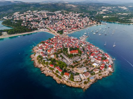 Primosten, Croatie - Vue aérienne de la péninsule de Primosten et de la vieille ville par une journée d'été ensoleillée en Dalmatie, Croatie avec des toits rouges et de l'eau de mer bleu turquoise sur la côte de la mer Adriatique