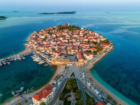 Primosten, Croatia - Aerial view of the old town of Primosten peninsula, St. George's Church on a sunny summer morning in Dalmatia, Croatia. Blue and mooring yachts at the marina at sunrise on the Adriatic sea coast