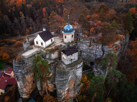 Foto de Sloup v Cechach, República Checa - Vista aérea del Castillo de Rock Sloup en el norte de Bohemia en otoño con follaje verde y naranja - Imagen libre de derechos