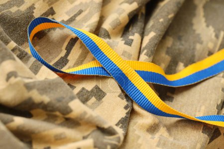 Tela de camuflaje militar digital pixelada con cinta en colores azul y amarillo. Atributos del uniforme de soldado patriótico ucraniano