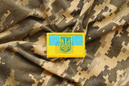 Tissu de camouflage militaire numérique pixellisé avec drapeau ukrainien et armoiries sur chevron en bleu et jaune. Attributs de l'uniforme de soldat ukrainien