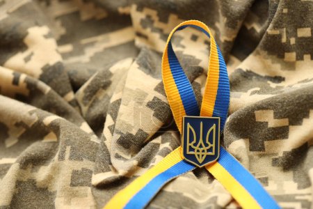 Photo for Pixeled digital military camouflage fabric with ukrainian flag and coat of arms on stripes ribbon in blue and yellow colors. Attributes of ukrainian soldier uniform - Royalty Free Image