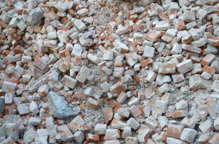 Pile of broken red bricks and fragments of concrete from destroyed building. Broken bricks close up demolition or destruction of buildings. Construction debris