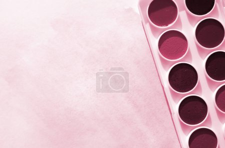 Photo for A new set of watercolors lies on a sheet of paper, which shows an abstract watercolor drawing in the form of blue strokes. Image toned in Viva Magenta, color of the 2023 year - Royalty Free Image