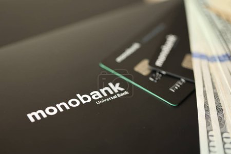 Téléchargez les photos : KYIV, UKRAINE - 7 JUILLET 2023 : Monobank black banking cartes plastiques avec de l'argent sur la table - en image libre de droit