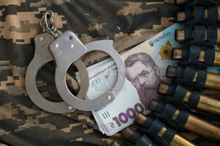 Maschinengewehrgeschosse der ukrainischen Armee, Handschellen und Hrywnja-Scheine auf Militäruniformen. Konzept der Bestechung und Kriegsverbrechen während des Krieges in der Ukraine