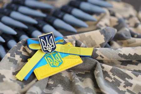 Ukrainisches Symbol und ein Maschinengewehrgürtel auf der Tarnuniform eines ukrainischen Soldaten. Das Konzept des Krieges in der Ukraine, Patriotismus und der Schutz Ihres Landes vor russischen Besatzern