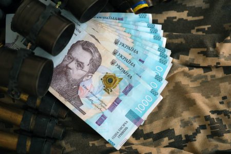 Photo for Ukrainian army machine gun belt shells and bunch of hryvnia bills on military uniform. Payments to soldiers of the Ukrainian army, salaries to the military. War in Ukraine - Royalty Free Image