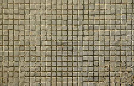 Foto de La textura de la antigua pared de hormigón, con un recubrimiento de baldosas poco profundas de forma cuadrada, pintadas de gris. Imagen de fondo de una pared de muchos azulejos blancos cuadrados - Imagen libre de derechos
