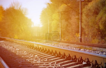 Photo for Autumn industrial landscape. Railway receding into the distance among green and yellow autumn trees. - Royalty Free Image