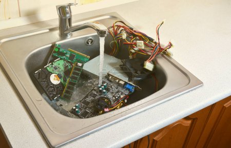 Foto de Limpieza del concepto de hardware. Lavando la placa base, el disco duro y la fuente de alimentación de la computadora en el fregadero de la cocina. También un símbolo para cometer un gran error - Imagen libre de derechos