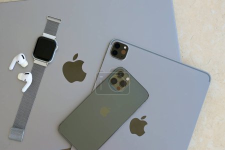 Foto de KYIV, UCRANIA - 4 MAYO 2023: dispositivos de la marca Apple iPhone, ipad y airpods con reloj de manzana se encuentra en el cuerpo del macbook de cerca - Imagen libre de derechos