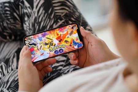 Téléchargez les photos : Pokemon GO jeu iOS mobile sur iPhone 15 écran de smartphone dans les mains des femmes pendant le gameplay mobile. Jeux mobiles et divertissement sur appareil portable - en image libre de droit