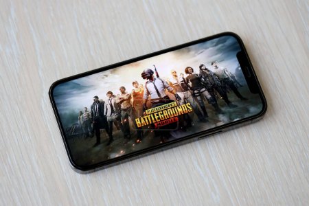 Photo for PUBG PlayerUnknowns Battlegrounds mobile iOS game on iPhone 15 smartphone screen on wooden table during mobile gameplay. Mobile gaming and entertainment on portable device - Royalty Free Image
