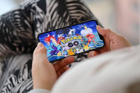Téléchargez les photos : Pokemon GO jeu iOS mobile sur iPhone 15 écran de smartphone dans les mains des femmes pendant le gameplay mobile. Jeux mobiles et divertissement sur appareil portable - en image libre de droit