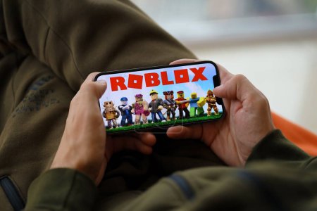 Photo for Roblox mobile iOS game on iPhone 15 smartphone screen in male hands during mobile gameplay. Mobile gaming and entertainment on portable device - Royalty Free Image