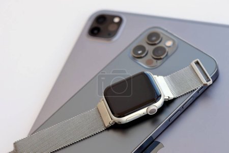 Foto de KYIV, UCRANIA - 4 MAYO 2023: dispositivos de la marca Apple iphone, ipad con Apple reloj se encuentra en el cuerpo del macbook de cerca - Imagen libre de derechos