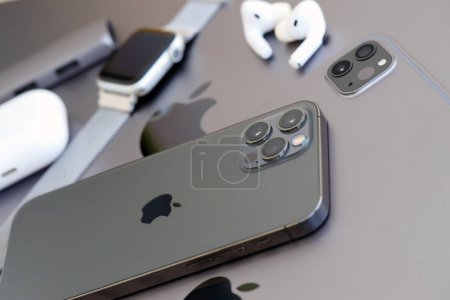 Foto de KYIV, UCRANIA - 4 MAYO 2023: dispositivos de la marca Apple iPhone, ipad y airpods con reloj de manzana se encuentra en el cuerpo del macbook de cerca - Imagen libre de derechos