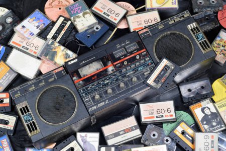 Foto de KYIV, UCRANIA - 4 DE MAYO DE 2023: Casetes de audio apilados y colocados alrededor de un reproductor de discos obsoleto. Memoria de un tiempo pasado - Imagen libre de derechos