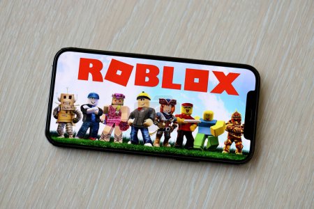 Photo for Roblox mobile iOS game on iPhone 15 smartphone screen on wooden table during mobile gameplay. Mobile gaming and entertainment on portable device - Royalty Free Image