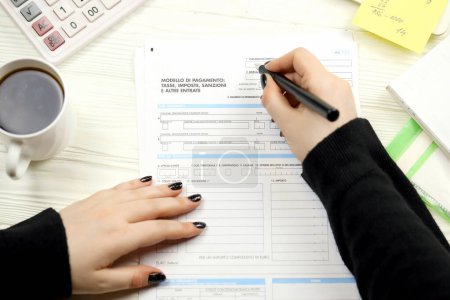 Photo for Accountant fill italian tax form F23 Payment model taxes duties penalties and other revenues in end of tax period. Taxation and paperwork routine in Italy - Royalty Free Image