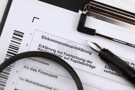 Photo for German annual income tax return declaration form blank on A4 tablet lies on office table with pen and magnifying glass close up - Royalty Free Image