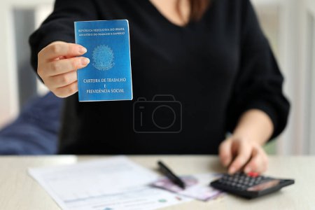 Photo for Woman boss gives a brazilian work card and social security blue book to us in employment office close up - Royalty Free Image
